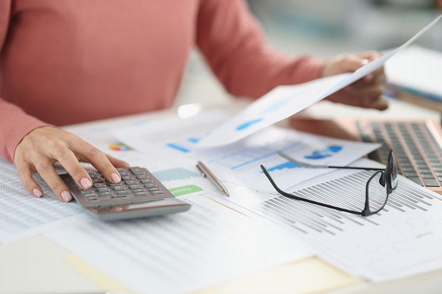 A San Juan College student using a calculator to check numbers on printed accounting charts